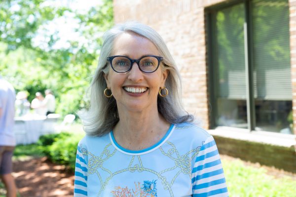 smiling woman with glasses standing outside by window